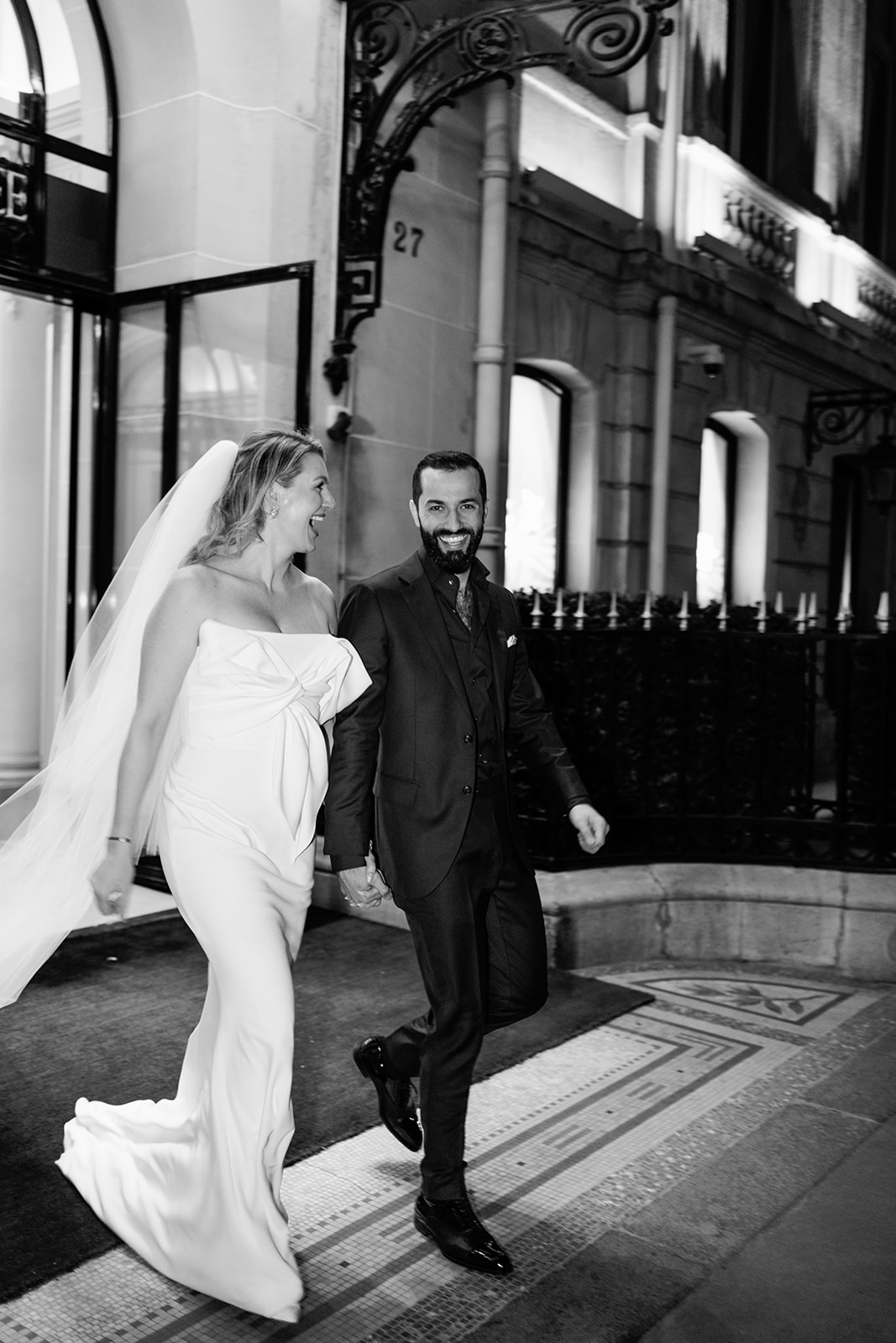 Bride and groom running outside Hôtel Plaza Athénée in black and white